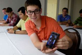 A Nashville seminarian holds a cellphone Aug. 12 showing a video chat to a fellow seminarian in Rome. A former BBC executive will help reform the Vatican’s media services after being appointed to the media committee.