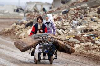 A brother and sister transport their salvaged belongings from their destroyed house Jan. 2 in Aleppo, Syria.