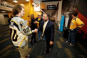 Tom Cigarran, chairman of the Nashville Predators hockey team, with yellow hat, and CEO Sean Henry, center, greet fans in Bridgestone Arena May 16 before Game 3 of the Western Conference finals of the Stanley Cup Playoffs in Tennessee. The two men are active in the Nashville Catholic community.