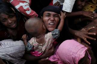  A Rohingya woman holds her infant as she scuffles to receive relief aid Nov. 28 in the Kutupalong refugee camp near Cox&#039;s Bazar, Bangladesh.