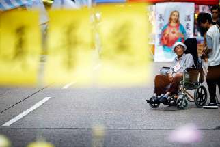 An elderly woman in a wheelchair is pushed near an improvised church in the area occupied by pro-democracy protesters in Mongkok shopping district in Hong Kong Oct. 30.