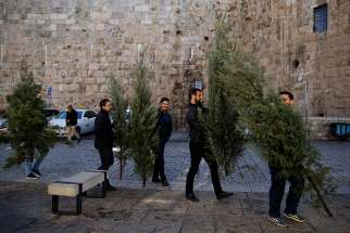 People carry Christmas trees, handed out annually by the Jerusalem municipality, in Jerusalem&#039;s Old City. The status quo of Jerusalem should remain as is until an agreement about the holy city&#039;s status is reached by Palestinians and Israelis, said Archbishop Pierbattista Pizzaballa, apostolic administrator of the Latin Patriarchate of Jerusalem.