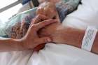 A nurse touches the hand of a palliative care patient.