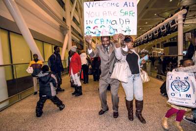 The joy is quite widely evident on the face of Tehetche Herve Mility as he greets members of his family among 50 refugees who arrived in Toronto with the aid of the Archdiocese of Toronto’s Office for Refugees. Martin Mark, right, the executive director, says it is moments like these that make the countless hours devoted to securing a place in Canada for people fleeing oppression in their homelands all worthwhile