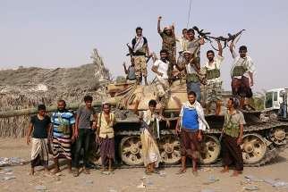 Tribal fighters loyal to the Yemeni government pose for a photo by a tank near Hodeida, Yemen, June 1. 