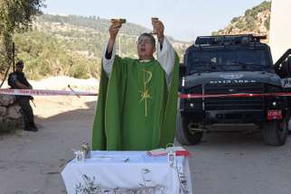 Fr. Aktham Hijazin of Beit Jalla, West Bank, celebrates Mass Sept. 3 in front of Israeli border police. Israel is uprooting the trees to make the way for the controversial separation barrier in the Cremisan Valley.