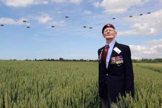 British World War II veteran Frederick Glover poses for a photo June 5 as soldiers parachute down during D-Day commemoration ceremonies in Ranville, France. About 18 heads of state were to attend ceremonies bringing together 3,000 veterans along France&#039;s Normandy coast where Allied forces landed on June 6 , 1944 in a seaborne invasion that sped up the defeat of Nazi Germany in World War II.