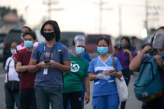 Workers wearing protective masks wait for shuttle services in Manila, Philippines, Aug. 4, 2020, the first day of the government&#039;s reimplementation of a stricter pandemic lockdown.