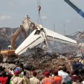 People watch as a crane lifts the tail of a Dana Air plane after it crashed in Lagos, Nigeria, June 4. The crash claimed the lives of all 153 people on board, as well as six people in a building the plane struck. 