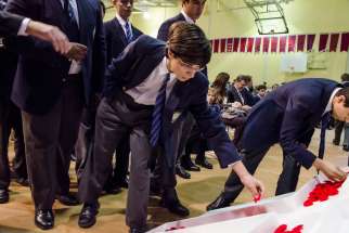 A St. Michael&#039;s College School student lays a poppy inside a hollowed-out cross.