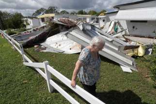 Cherie Monroe pauses after looking at the roof of her home Oct. 9 in the aftermath of Hurricane Matthew in Port Orange, Fla.