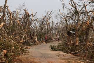 People walk past damaged trees May 4, 2019, following Cyclone Fani in Puri, India. The powerful cyclone ripped through eastern India and sideswiped Bangladesh, May 3, leaving a trail of destruction and more than 30 deaths.