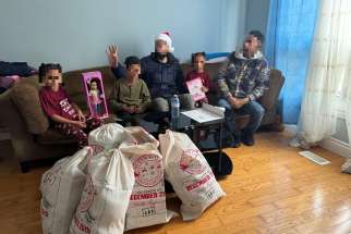 An anonymous newcomer family sit with gifts donated to them through the Diocese of Hamilton’s Office for Refugees gift- giving initiative last Christmas. (Faces are blurred to protect privacy)