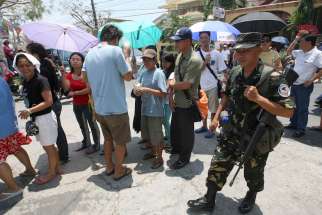A Philippine air force trooper walks past voters lining up outside a precinct on election day in 2010 in Las Pinas.