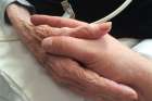 A son holds his mother&#039;s hands at a hospice care facility moments before her death from ovarian cancer in 2015.