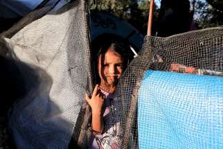 A girl looks out from a makeshift tent Sept. 17 at a camp for refugees and migrants on the island of Lesbos, Greece.