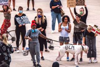 A woman and her dog carry the anti-racism message at Nathan Phillips Square in Toronto on June 5.