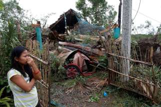 A woman in Bangui, Philippines, stands outside her house damaged by a fallen tree Oct. 20 after Typhoon Haima hit. Heavy damage was reported to homes and farmland in the northern Philippines after the strongest storm in three years struck overnight.