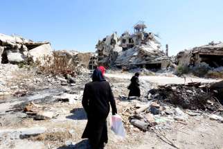 People walk amid rubble Sept. 19 in the city of Homs, Syria. Chaldean Catholic bishops at their annual synod calls for peace in the Middle East and the liberation of Islamic State controlled areas.
