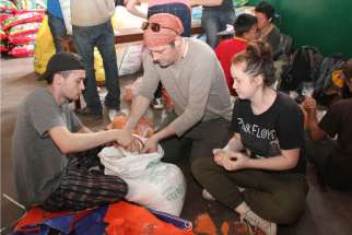 Canadian tourists Tave Teloye and his children Alan and Juliet prepare lentil packets for earthquake victims May 1 at Assumption Catholic Church in Lalitpur, Nepal.