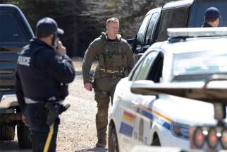Royal Canadian Mounted Police stand along a road in Portapique, Nova Scotia, April 19, after a shooter went on 12-hour rampage that left at least 19 people dead before police killed him.