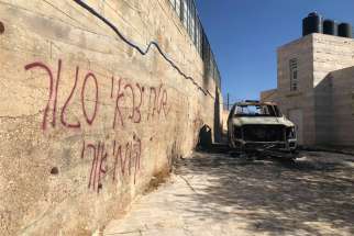 Graffiti is seen in Hebrew on a wall next to a car was burned in the Palestinian town of Taybeh, east of Ramallah, West Bank. The Assembly of Catholic Ordinaries of the Holy Land condemned vandalism attacks in two Arab villages and called on Israeli authorities to &quot;investigate seriously&quot; what they termed hate crimes.