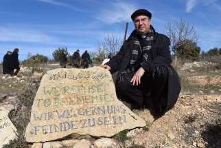 Bishop Oscar Cantu of Las Cruces, N.M., kneels by a stone that reads &quot;We Refuse To Be Enemies&quot; Jan. 16 at the entrance to the Tent of Nations in the West Bank, near Bethlehem. Thirteen bishops from Europe and North America visited the area as part of the Holy Land Coordination.
