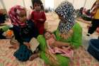 A displaced Iraqi woman carries her sleeping child July 16 at a refugee camp near Mosul, Iraq.