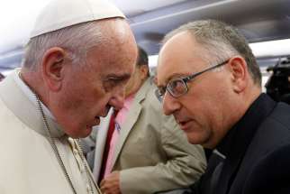 Pope Francis talks with the Rev. Antonio Spadaro, editor of La Civiltà Cattolica, as he meets journalists aboard his flight from Rome to Nairobi, Kenya, on Nov. 25, 2015.