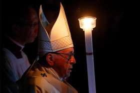 Pope Francis carries a candle as he arrives in procession to celebrate the Easter vigil in St. Peter&#039;s Basilica at the Vatican March 31.