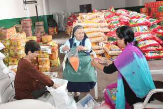 St. Joseph Sister Monique Niraula joins two other women in packing relief material for earthquake victims at Assumption Catholic Church in Lalitpur, Nepal, May 1.