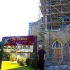 Fr. Jim Haley stands outside St. Peter’s Church, which is undergoing repair work to its bell tower.
