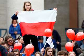 A girl holds a Polish flag as Pope Francis leads the Angelus March 19 in St. Peter&#039;s Square at the Vatican. 