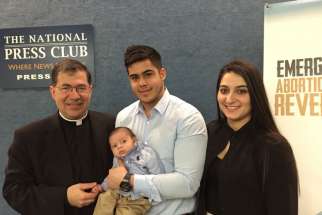 Father Frank Pavone, national director of Priests for Life, poses with Chris Caicedo, Andrea Minichini and their son, Gabriel Caicedo, following a news conference at the National Press Club in Washington Feb. 23 to call attention to a protocol to reverse RU-486 medical abortions. 