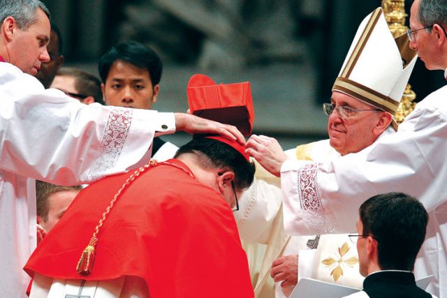 Pope Francis presents the red biretta to new Cardinal Gerald Lacroix of Quebec during a consistory in St. Peter’s Basilica at the Vatican Feb. 22.