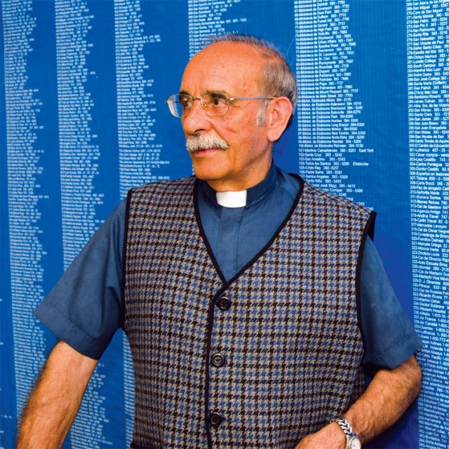 Fr. Fructuoso Garcia, who will leave Canada after 41 years on July 4, stands with pride in front of a large poster displaying the 2,000 phone numbers he’s memorized to gain publicity for his fundraising efforts that support churches in Latin America.