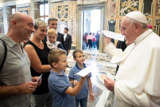 Pope Francis holds a paper airplane children gave him during a meeting at the Vatican Sept. 25, 2019, with members of the Emmanuel Community from Lecce, Italy, who are especially active in serving the poor, the disabled and marginalized. The pope told them they can fight off fatigue and discouragement by being with Christ as they work with so many people in difficulty.