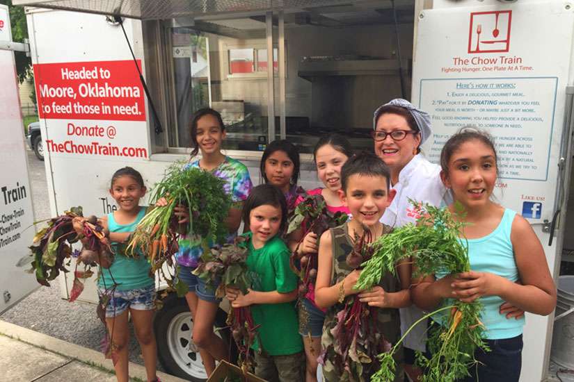 Joan Cheever poses with young farmers in front of the Chow Train food truck.