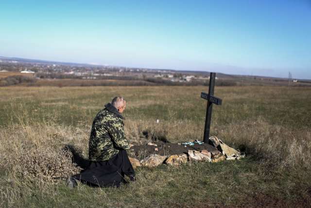 A priest kneels next to the grave of a soldier at a Ukrainian military camp near the eastern Ukrainian town Kramatorsk Oct. 26. Ukrainian President Petro Poroshenko claimed a landslide victory for pro-western parties Oct. 26 in the country&#039;s key parliamentary elections.