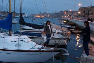 A woman on a boat talks with a friend in the evening in Valletta, Malta, in this March 25, 2010, file photo. The Vatican announced that Pope Francis will visit the island nation of Malta April 2-3, 2022.