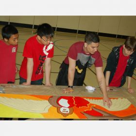 Wearing a black apron, Christian Carrizo shows Christian Alevedo, Kaleb Nquyen and Joshua Felix (left to right) some shading tips.