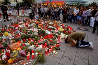 A man prays outside the Olympia shopping mall in Munich, Germany, July 23, where nine people were killed by an 18-year-old gunman.