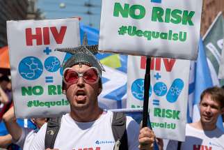 Participants march July 23 through the streets of Amsterdam, marking the opening of the 2018 International AIDS Conference. The man carries a sign supporting the belief that HIV-positive individuals with an undetectable viral load for six month are not contagious to others.