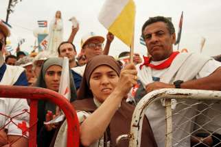 A nun waves a Vatican flag while attending Mass with Pope John Paul II in Havana Jan. 25, 1998. During his five-day visit to Cuba, the pope called for a spiritual renewal among the Cuban people.