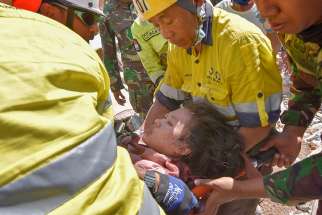 Rescue workers and soldiers carry a woman Aug. 7, who survived after being trapped in rubble following an earthquake on Lombok, Indonesia. At least 105 people have been confirmed dead after the magnitude 7 earthquake Aug. 5, a week after another powerful quake killed more than a dozen people. 