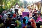 A group of  villagers in India listen to a Lok Manch speaker as he educates them on their rights under the National Food Security Act.