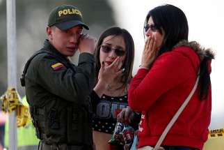A police officer and two women wipe away tears Jan. 17, 2019, close to the scene where a car bomb exploded in Bogota, Colombia.