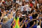 An audience member takes a selfie of himself with a photo of Blessed Oscar Romero behind him as Pope Francis arrives to lead his general audience in Paul VI hall at the Vatican Aug. 3. Bishops from Panama say Blessed Romero is an example of faith for youths.