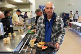 Bishop Donald J. Bolen of the Saskatoon, Saskatchewan, picks up breakfast at Saskatoon Friendship Inn June 18, after spending the night in a city park as part of the Sanctum Survivor homelessness challenge. He was one of 10 community leaders and celebrities who participated in the 36-hour event.