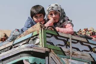 Young Syrian refugees are seen atop a vehicle at a camp in June in the village of Arsal, Lebanon. 